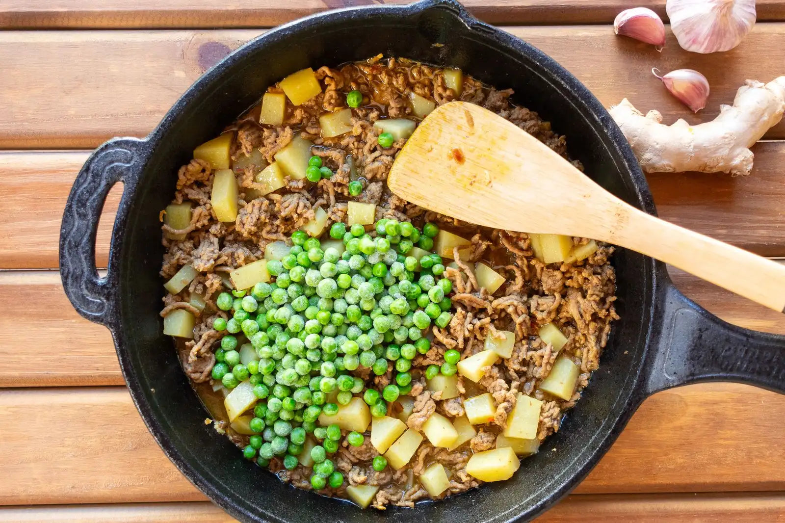 Taco seasoning being stirred into browned ground beef in a skillet