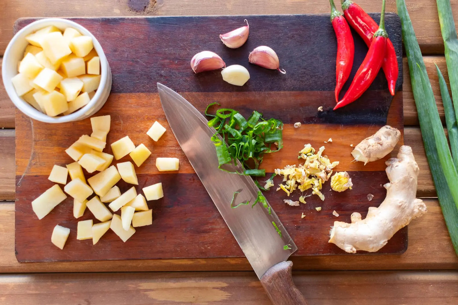 A fresh horseradish root and a knob of ginger on a wooden cutting board