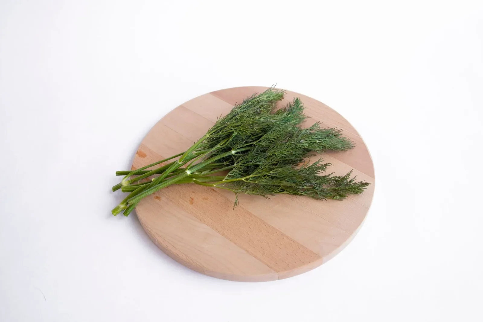 A bunch of fresh dill weed on a wooden cutting board