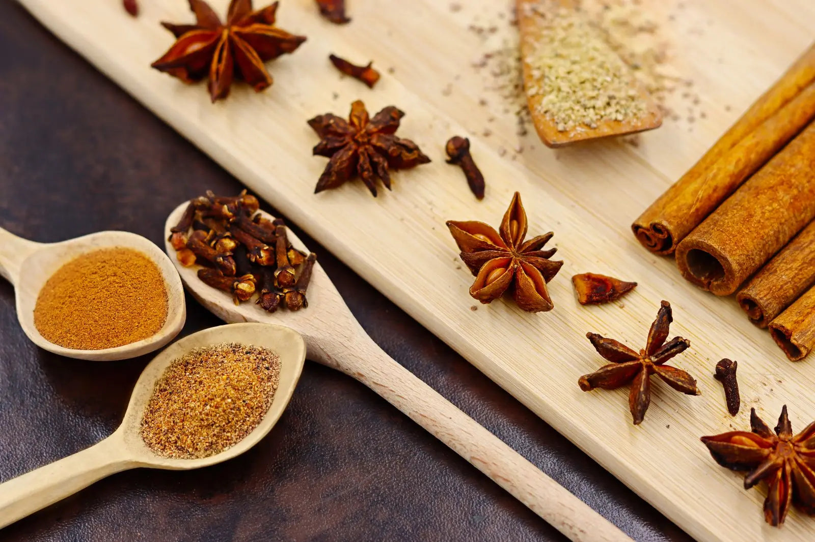 Cinnamon sticks and ground ginger in a small bowl on a wooden counter
