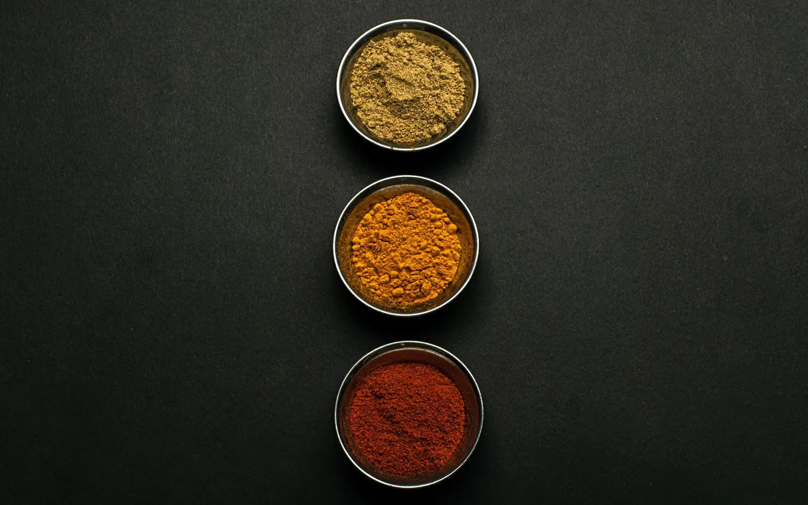 Small bowls of turmeric, ginger, and cinnamon arranged for a spice chart