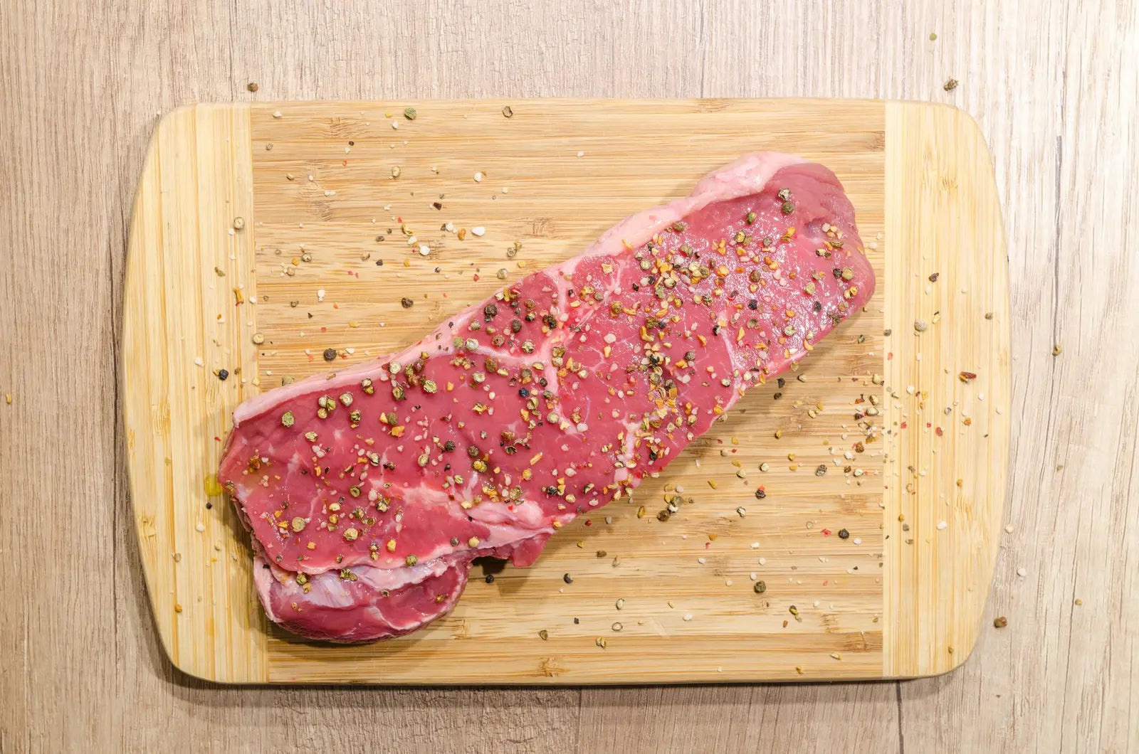 Raw steak seasoned with a dry rub on a cutting board