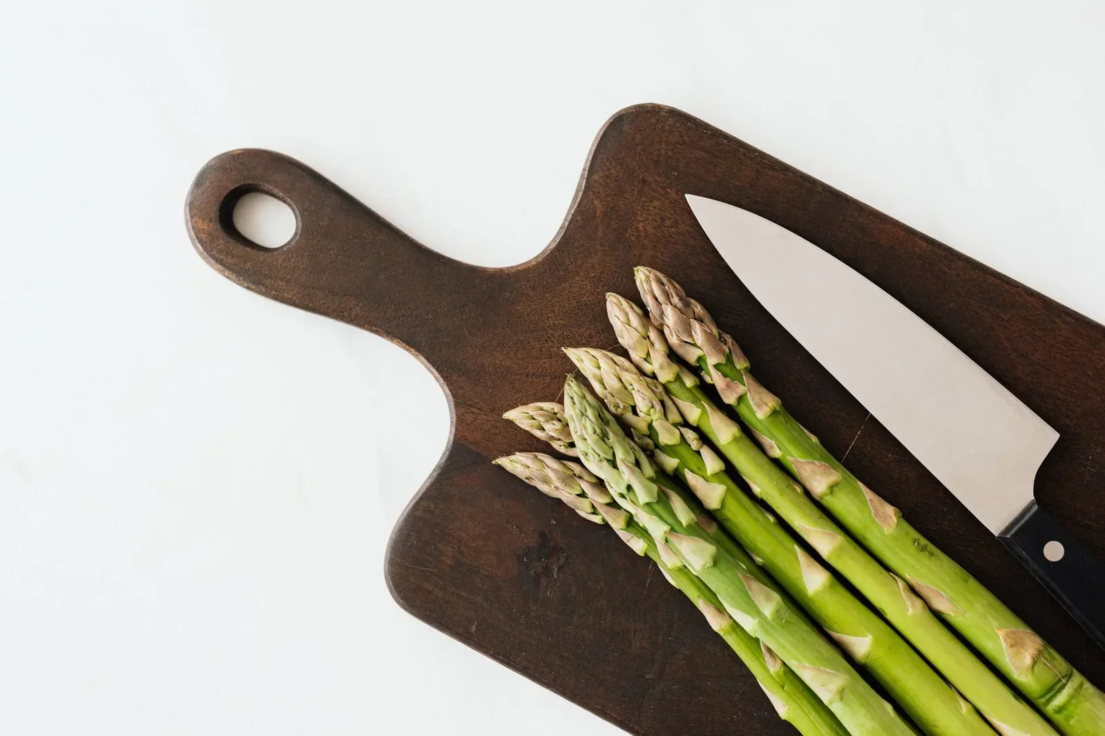 Fresh celery stalks and leaves on a cutting board next to a small bowl of dried celery flakes